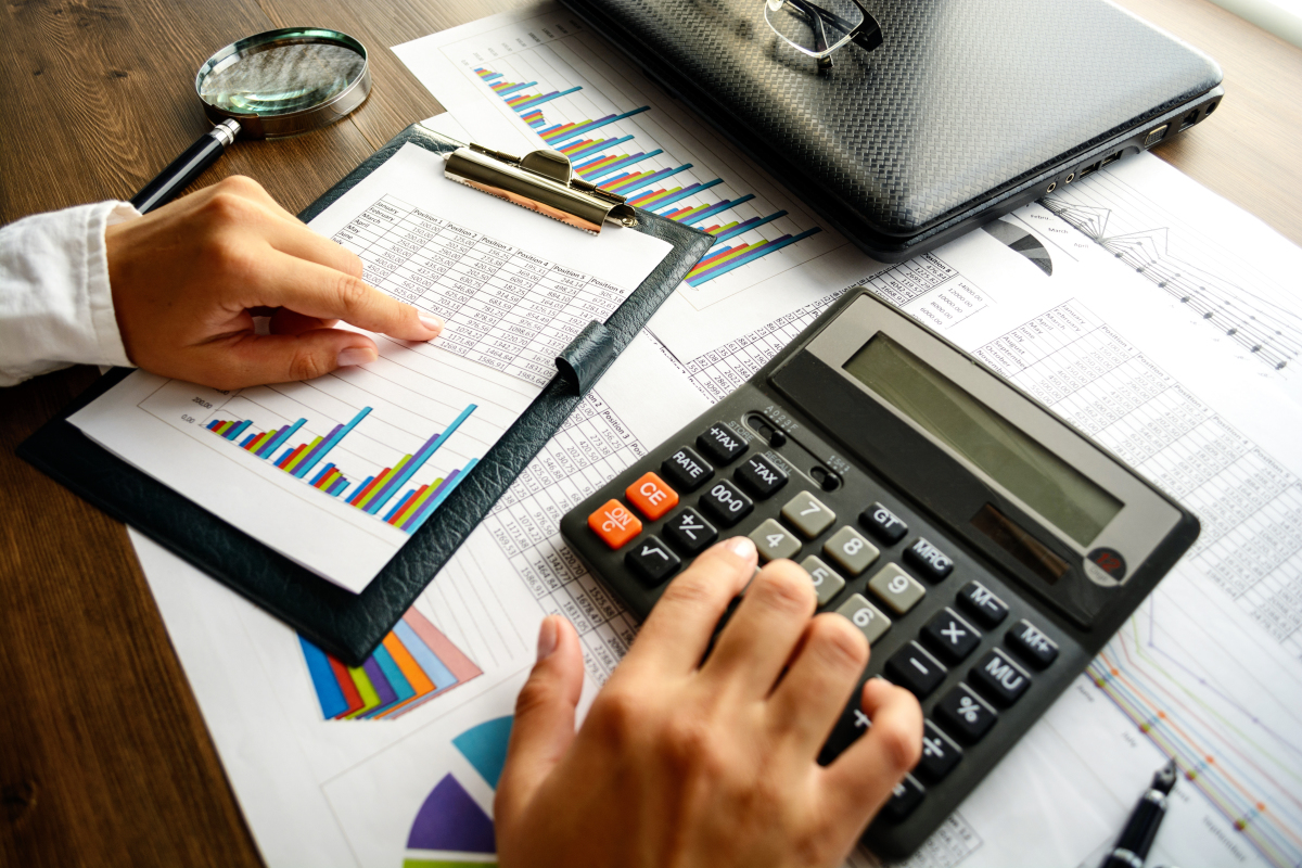 Mains d’un homme faisant des calculs avec calculatrice tableau de comptes et graphique