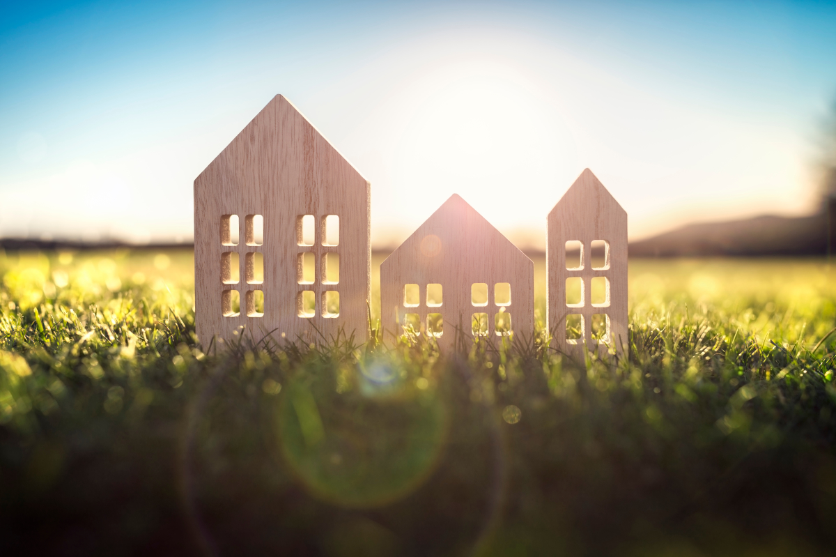 rénovation énergétique Toulouse – Figurines en bois d’immeubles et d’une maison dans l’herbe