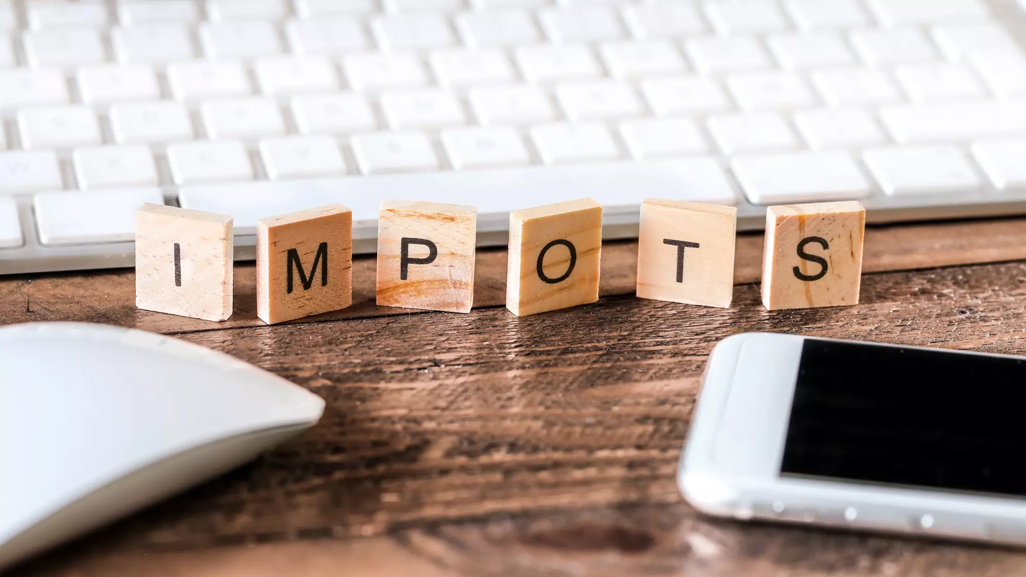 Lettres en bois écrivant le mot impôts posées sur un bureau
