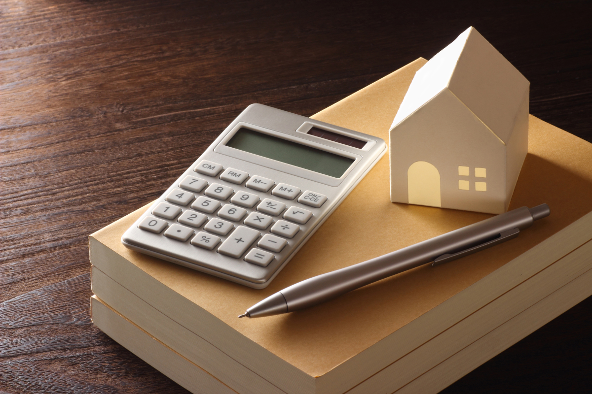 PTZ conditions revenus — Une calculette et une petite maison en papier placés sur un bloc-note