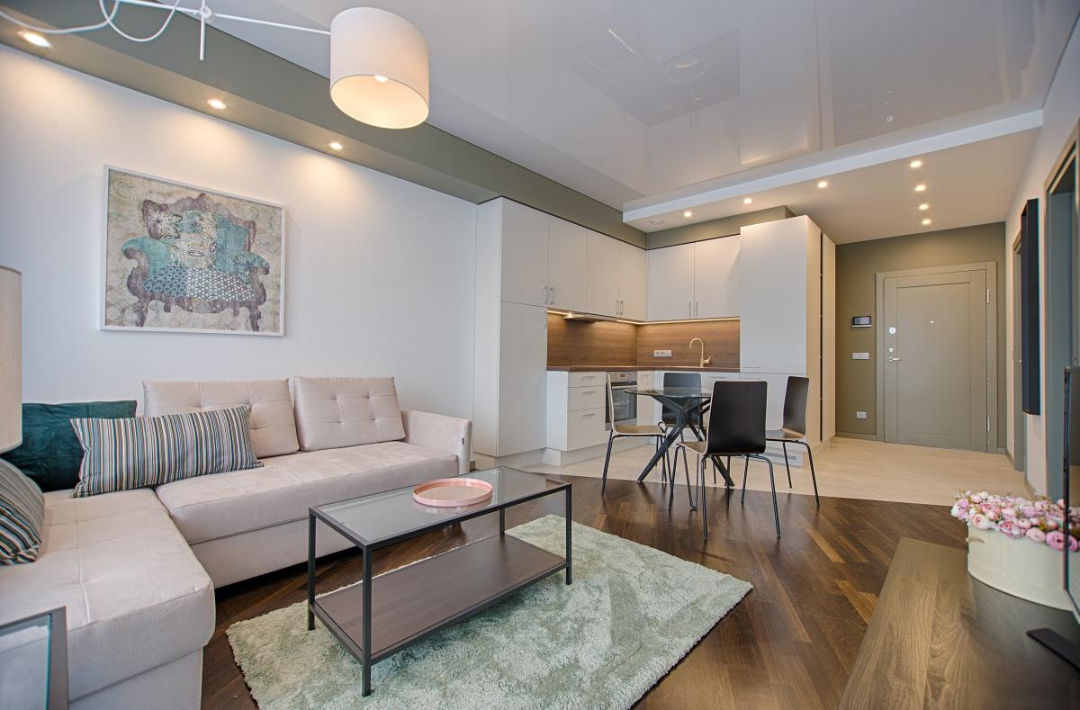 Investissement LMNP Toulouse - Un salon d'appartement neuf meublé avec une cuisine équipée en fond