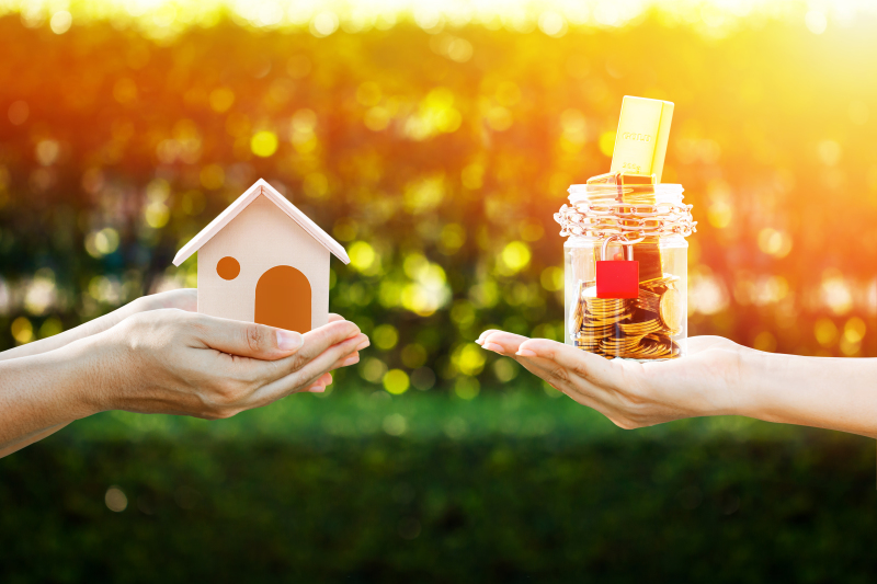 Inflation et prêt immobilier – Une main tenant une maison miniature et une main tenant un bocal rempli de pièces