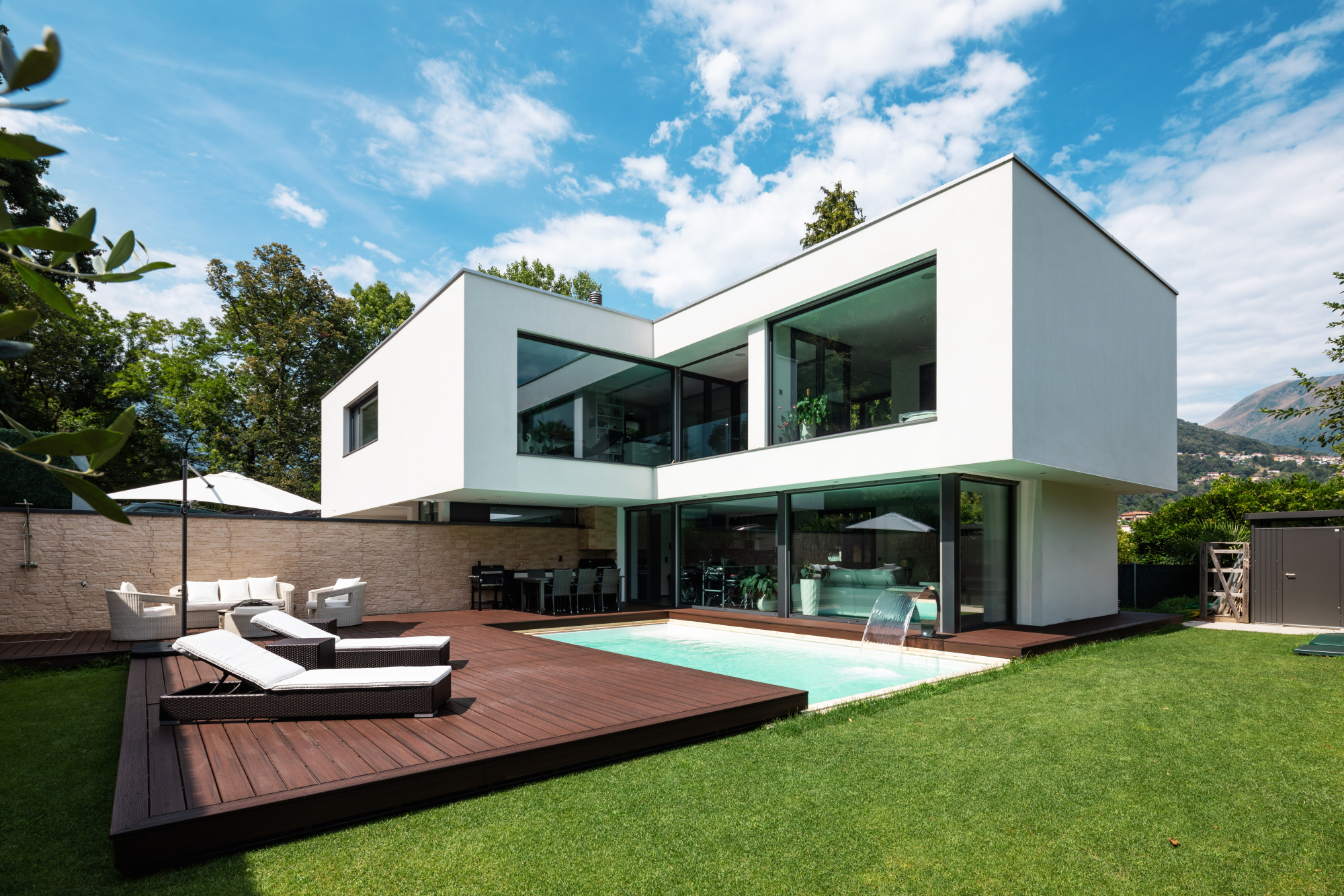 Une maison moderne avec une terrasse bois et une vaste surface gazonnée