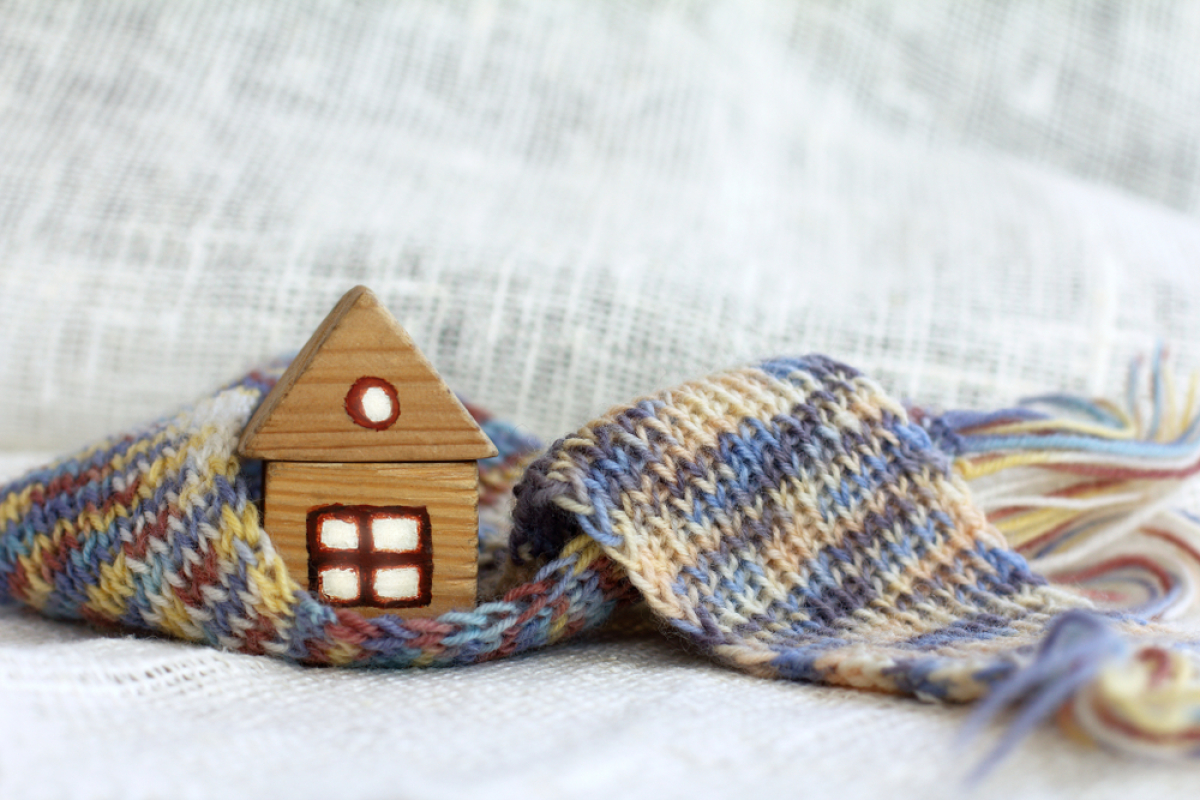 Gel des loyers – Une maison en bois miniature enveloppée dans une écharpe