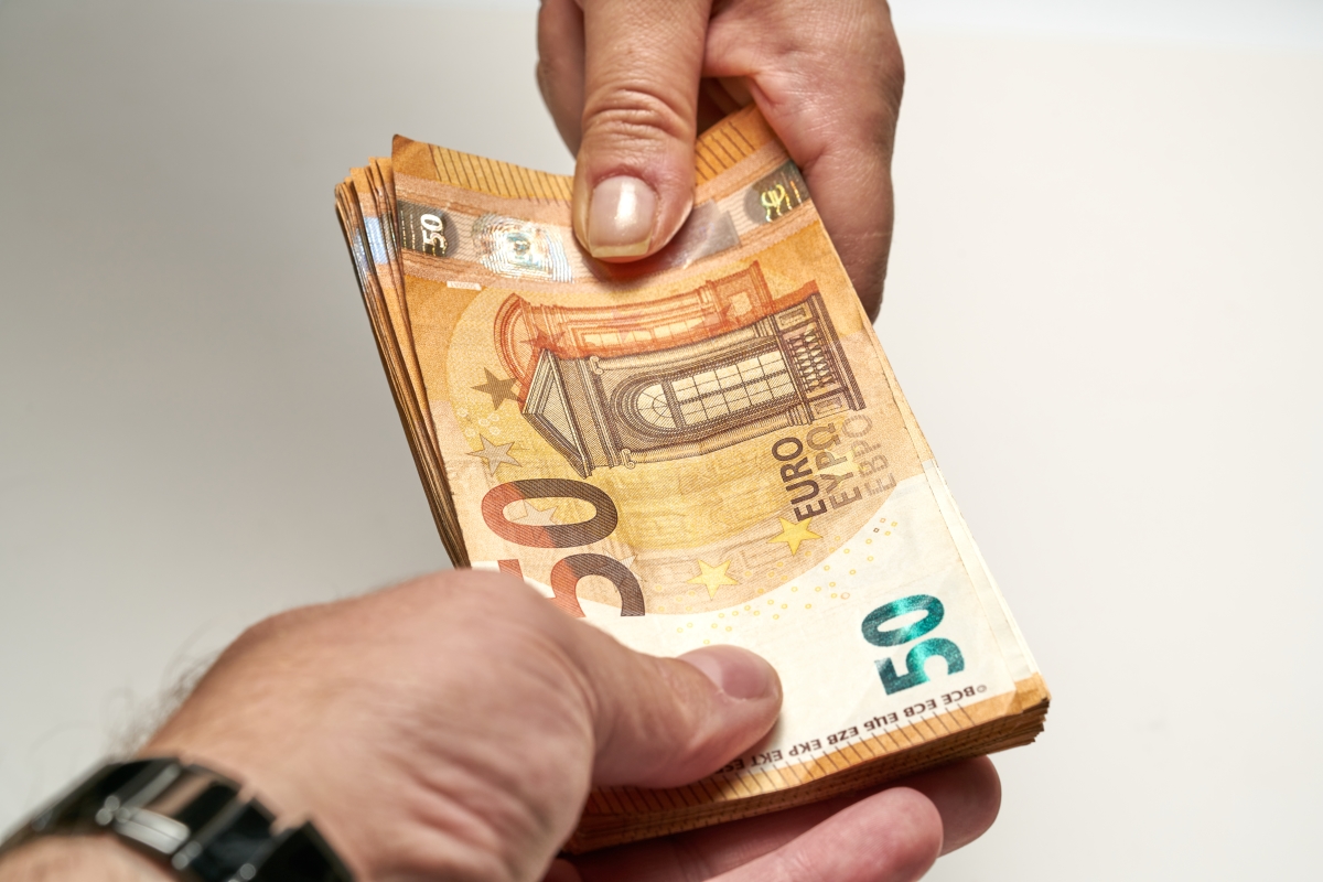 Dépôt de garantie VEFA — deux personnes échangent une liasse de billets de 50 euros