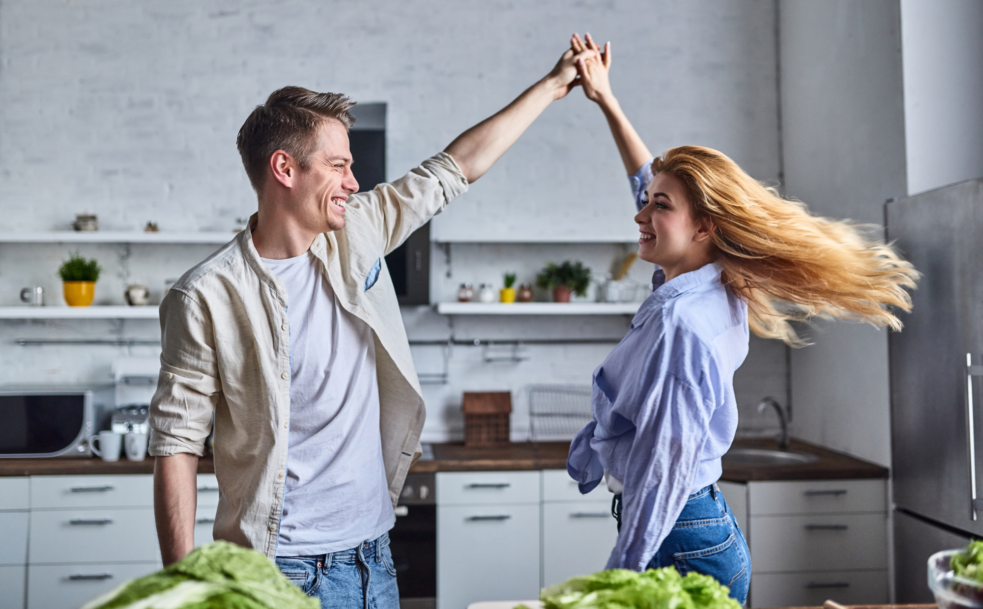 Un couple danse dans la cuisine de leur appartement