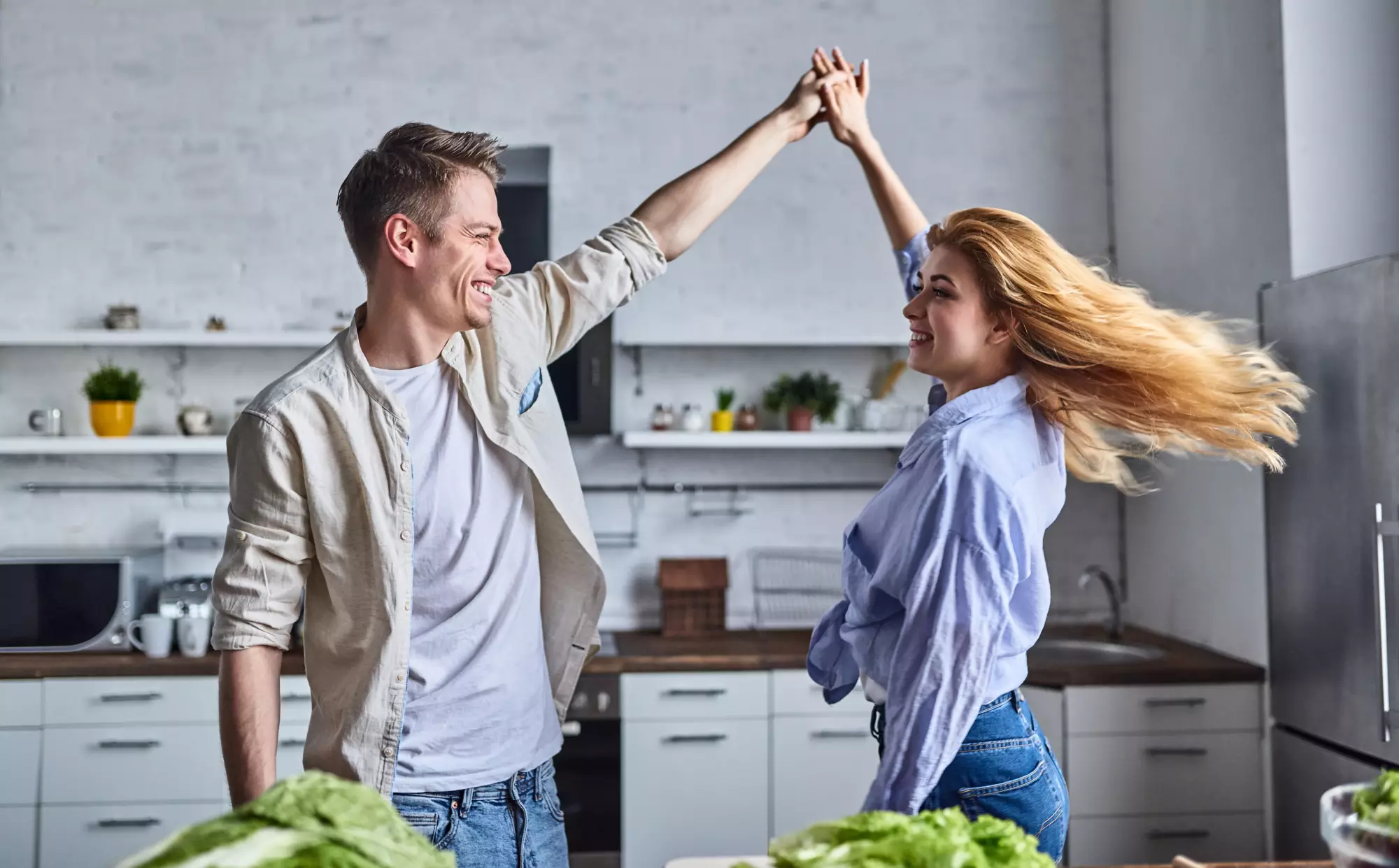 Un couple danse dans la cuisine de leur appartement