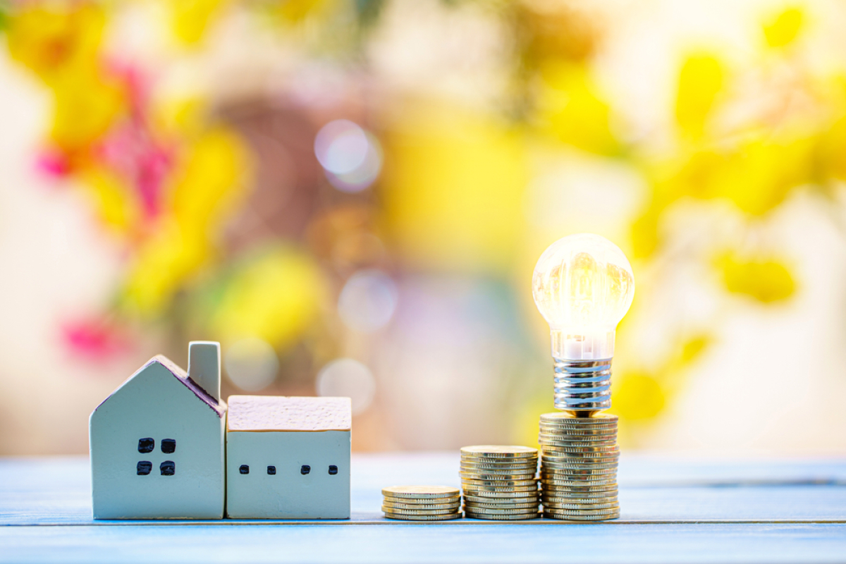 Frais achat immobilier neuf – Une maison miniature et une pile de pièces