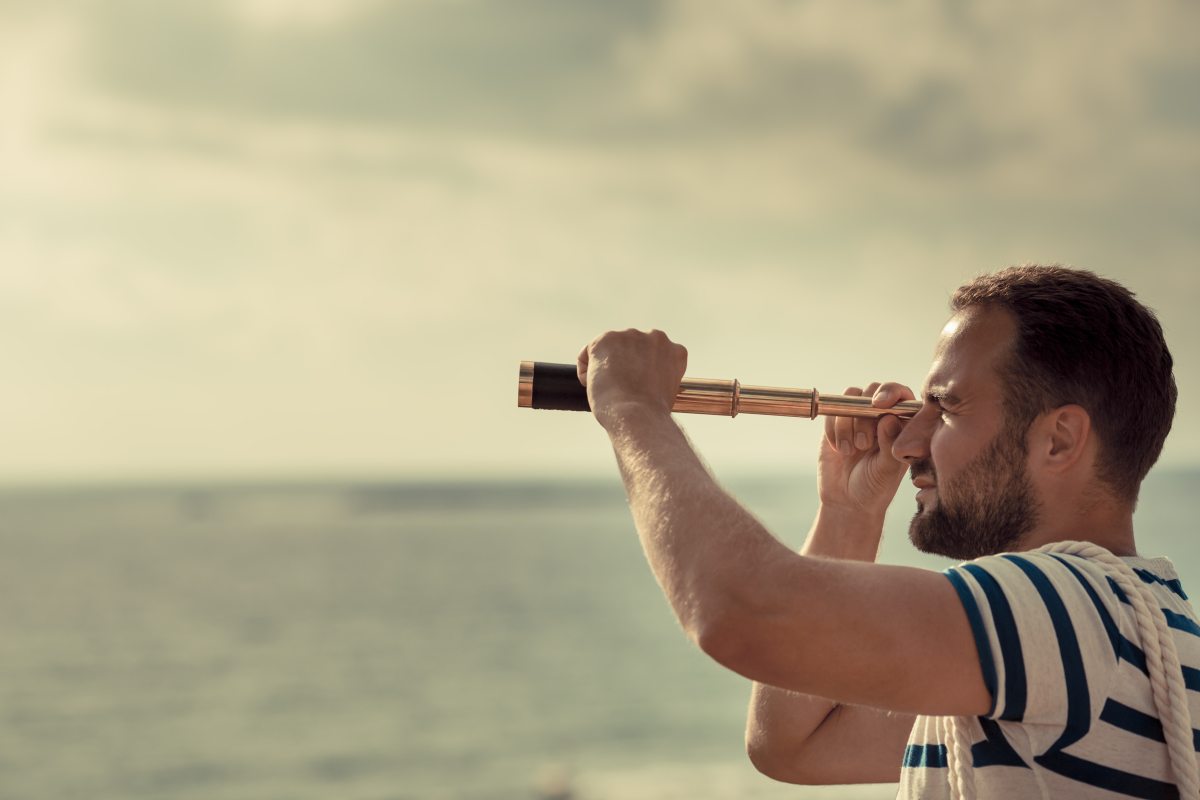 un homme regarde au loin avec une longue vue sur la mer