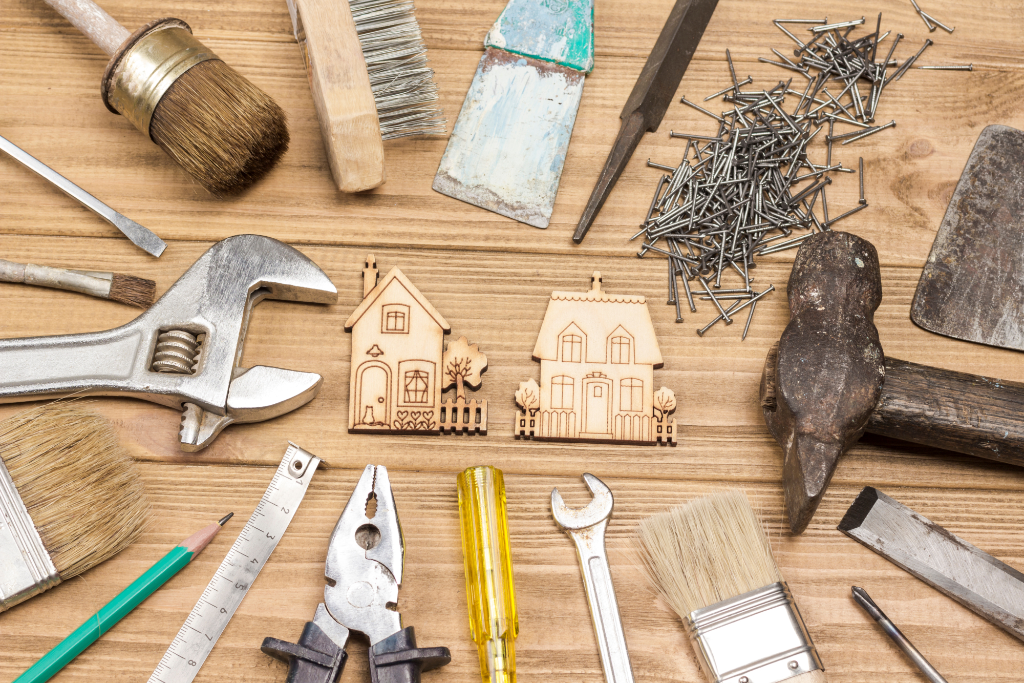 Des outils posés sur un bureau autour de maisons miniatures en bois