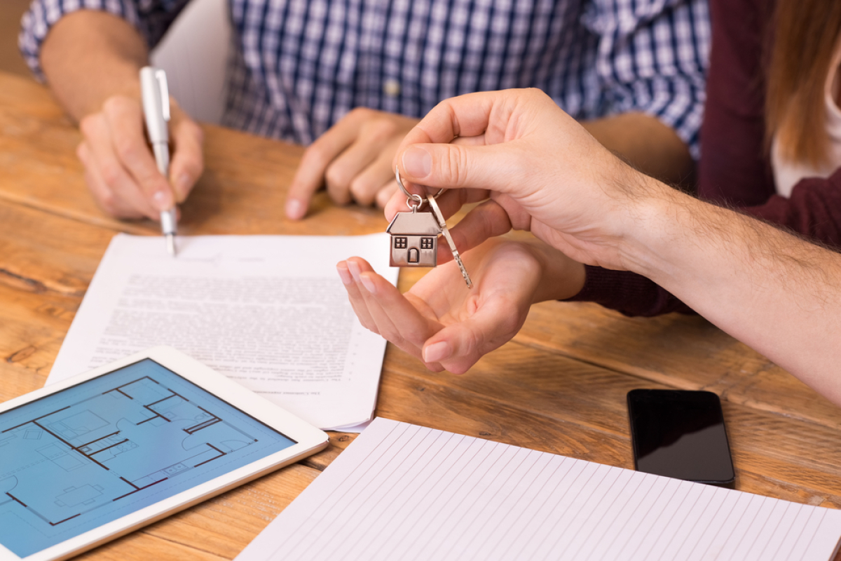 Faites confiance à IMMO9 pour votre achat immobilier neuf Brouardel – Canal du Midi – Sébastopol — Signature d’un contrat et échange de clés au-dessus d’un bureau
