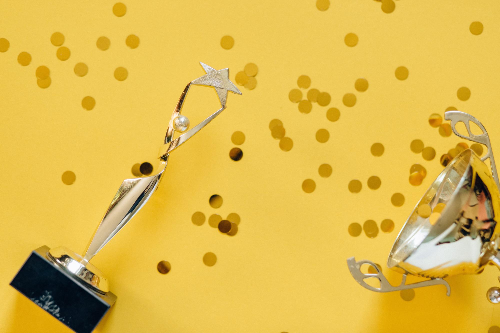 Des trophées sur fond jaune parsemés de confetti dorés