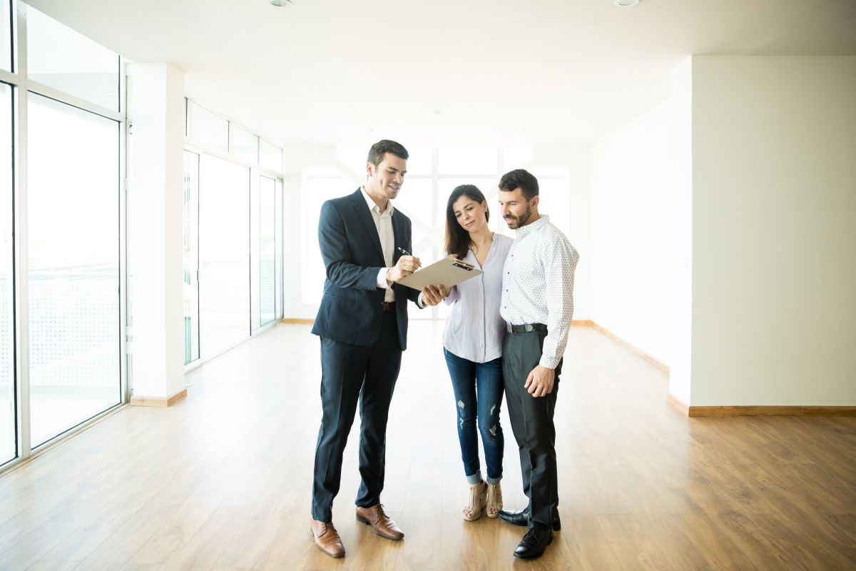 Garantie Loyers Impayés – un couple en train de s’entretenir avec un agent immobilier dans un appartement vide