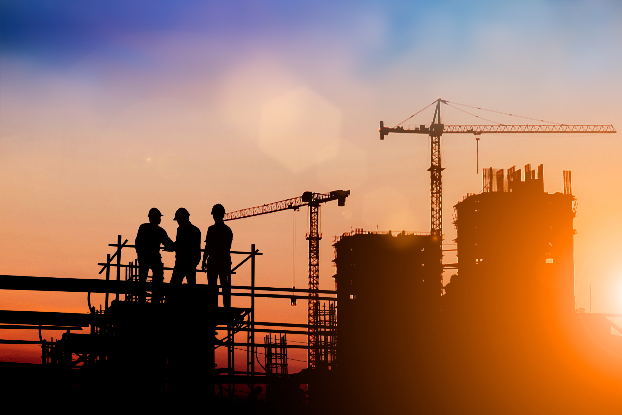 Des ouvriers sur un chantier devant le coucher de soleil