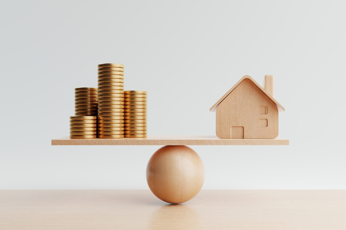 Conseil achat immobilier neuf – Des pièces de monnaie en équilibre avec une maison miniature