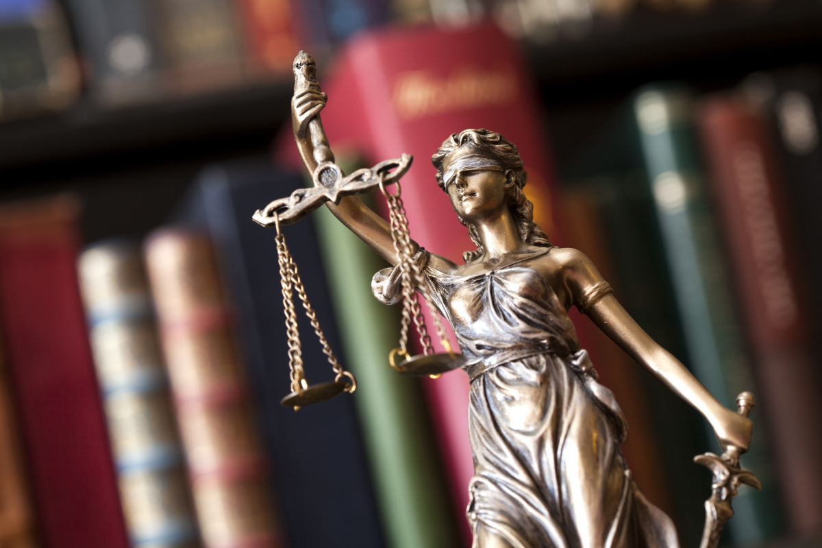 Louer un logement acheté avec PTZ — Une statue représentant la justice devant des livres de droit