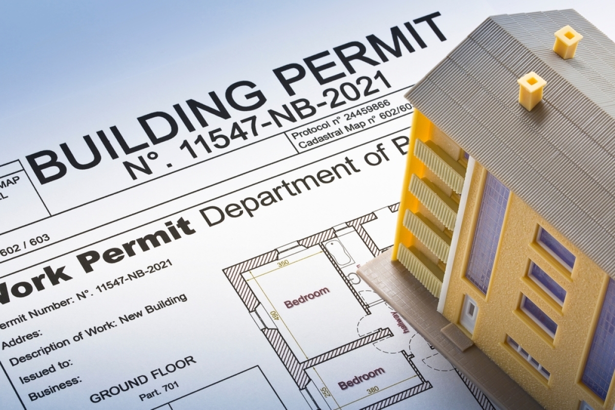 Un immeuble miniature posé sur un permis de construire