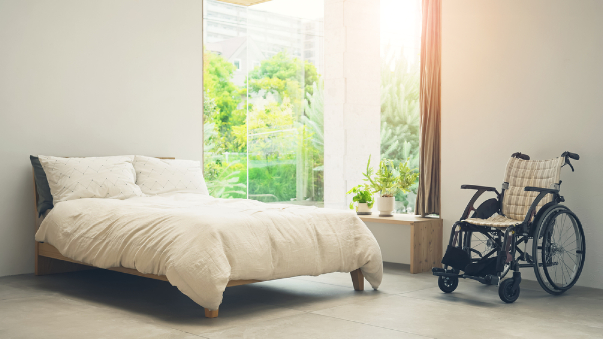 Normes PMR logement neuf – Une chambre avec un lit et un fauteuil roulant