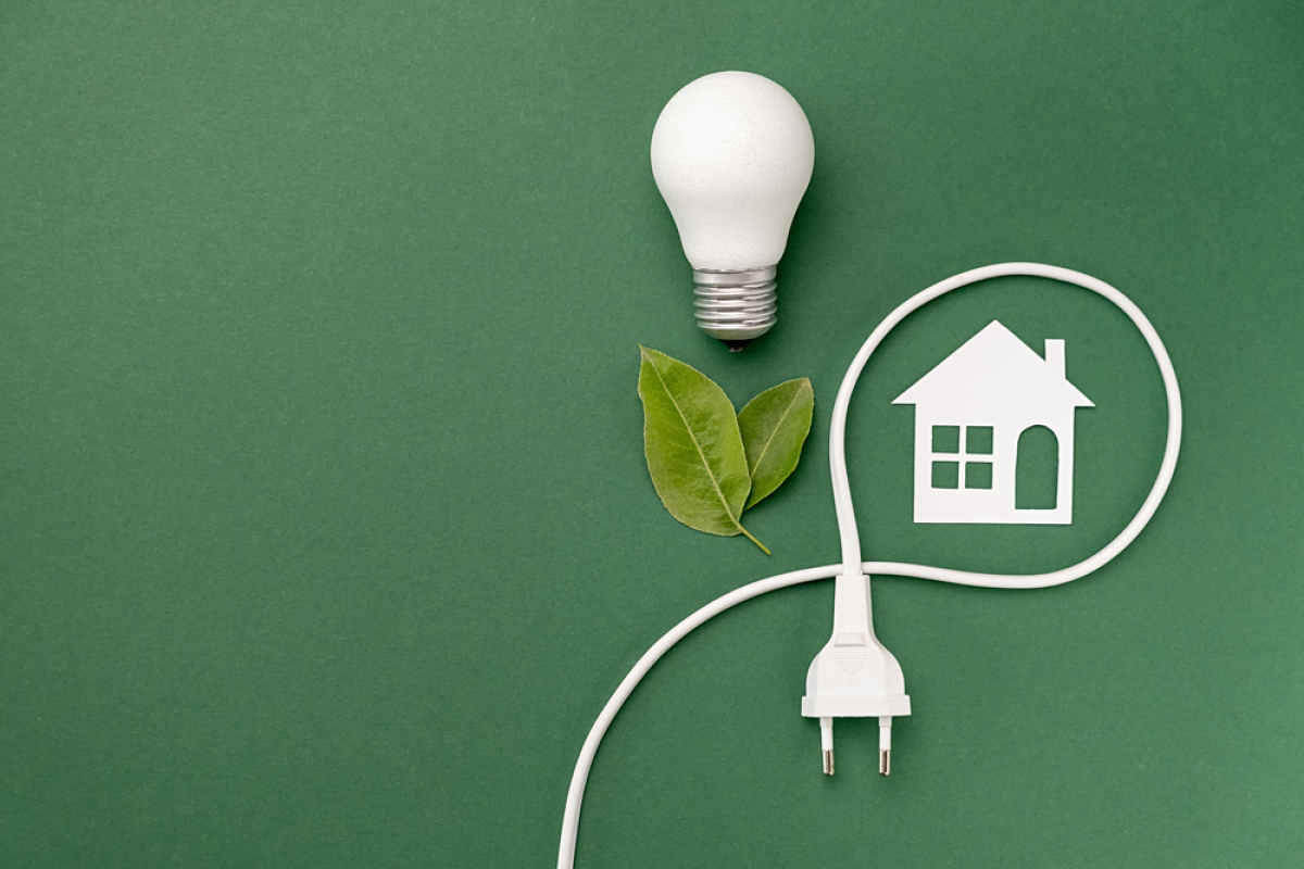 analyse cycle de vie bâtiment – un cordon électrique entoure une maison à côté de feuilles et d’une ampoule