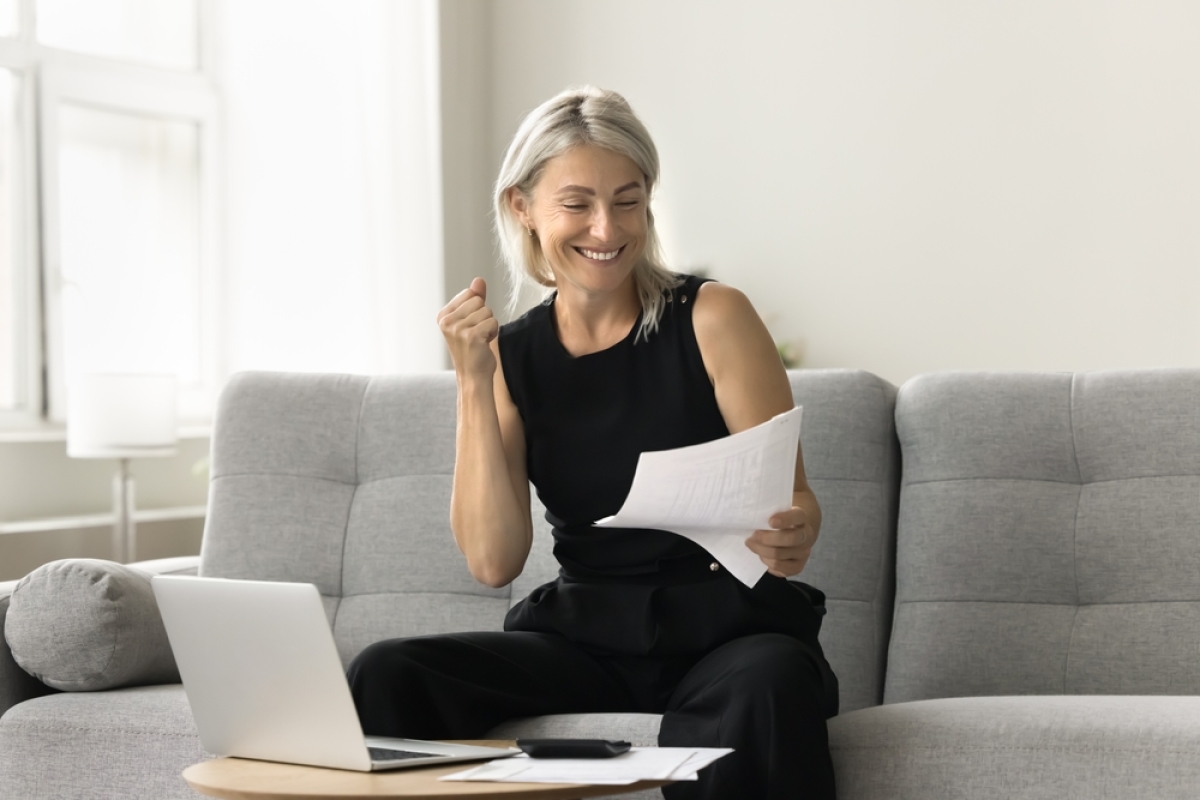 Comment louer une chambre chez soi – Une femme heureuse en train de faire sa déclaration d’impôts