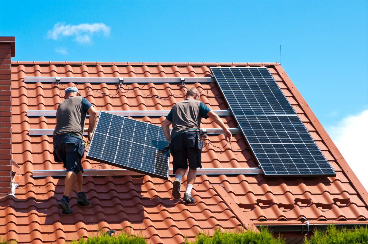 Deux ouvriers installent des panneaux solaires sur un toit