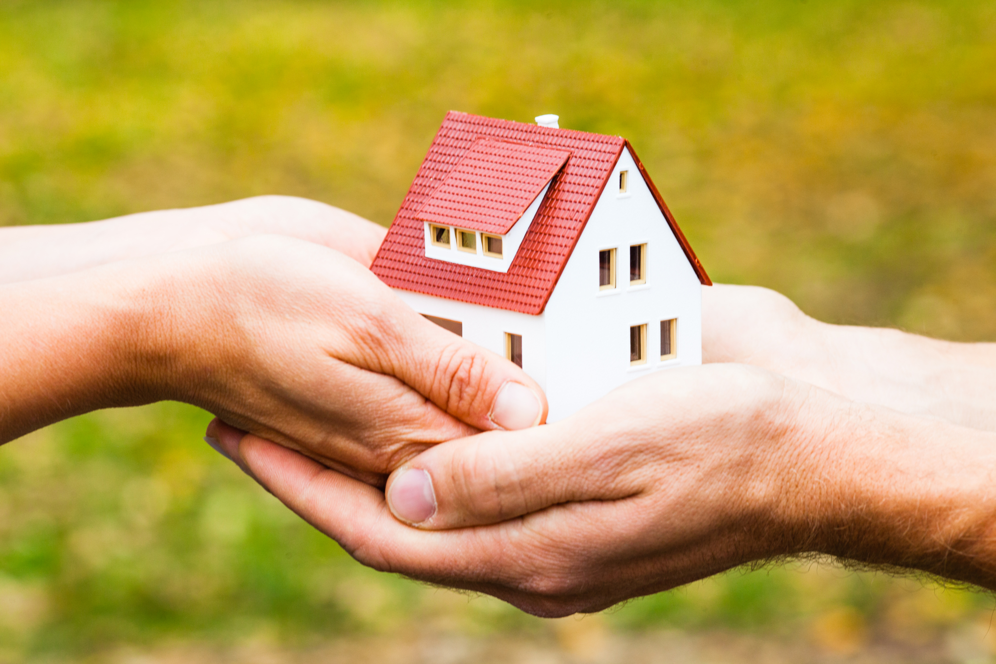 Une personne tend une maison miniature à une autre