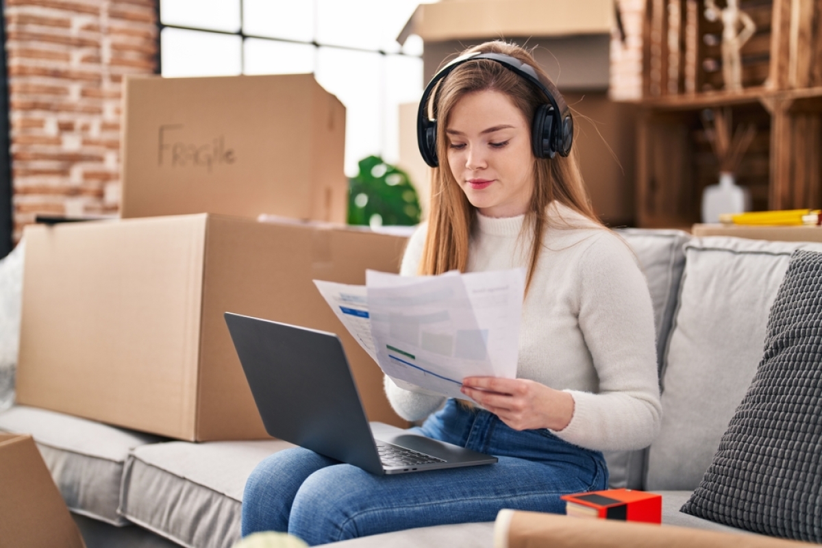 Budget étudiant première installation — une jeune étudiante commence à travailler à côté de ses cartons