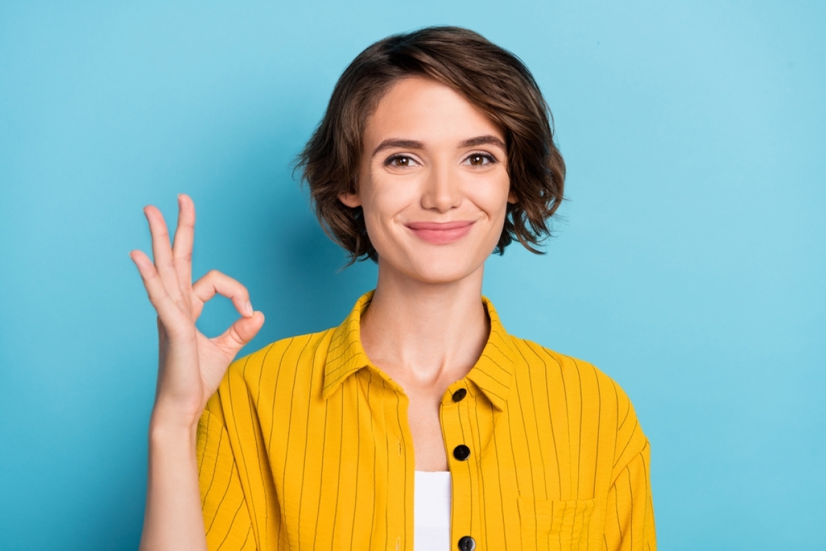 Accompagnement immobilier — une femme jeune et souriante fait le signe ok avec sa main gauche