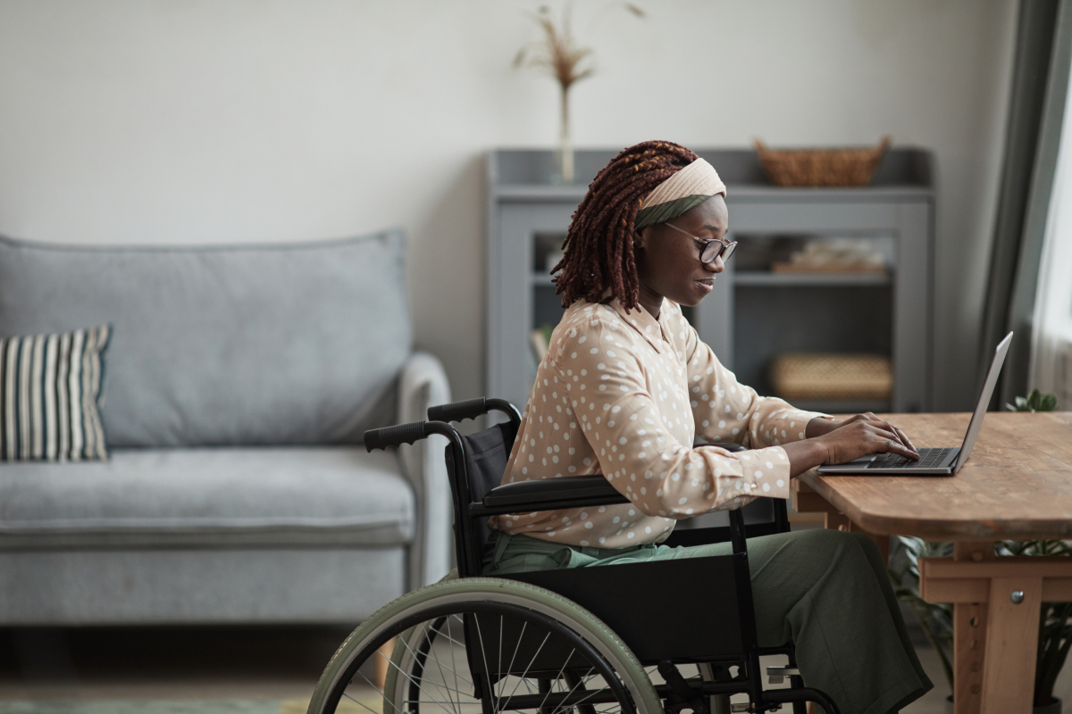 une femme en fauteuil attablée à son bureau