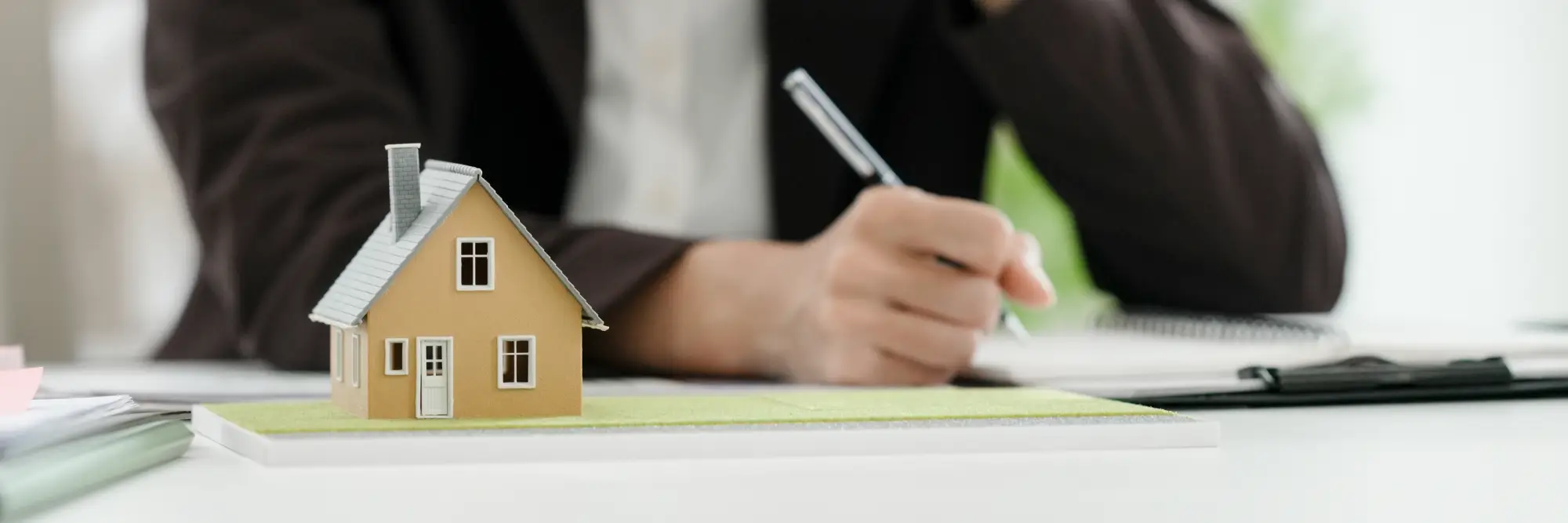 une maquette de maison neuve et une main tenant un stylo